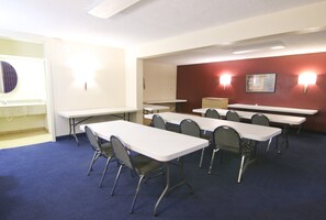 Un salón de conferencias con varias mesas y sillas, una pizarra y una pared de acento roja.