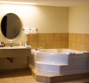 A bathroom with a large bathtub, a sink, and a mirror.