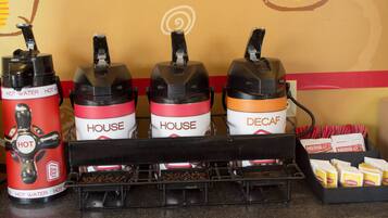 Een koffiehoek met drie koffieautomaten, waarvan er twee 'HOUSE' en 'DECAF' staan, en een rode automaat voor 'HEET WATER'.