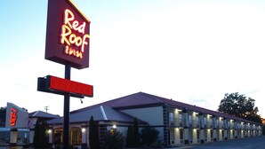 A Red Roof Inn with a large neon sign, a parking lot, and a building with multiple windows and balconies. - Red Roof Inn Somerset, KY (Somerset)
