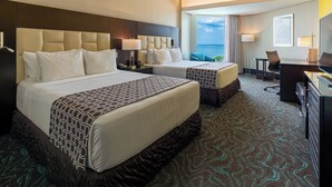A hotel room with two beds, a desk, a chair, and a view of the ocean. - Crowne Plaza Santo Domingo by IHG (Santo Domingo)