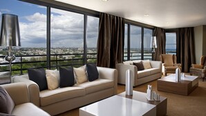 Ein geräumiges Wohnzimmer mit großem Fenster und Blick auf die Stadt, einer Sofagarnitur und zwei Couchtischen.