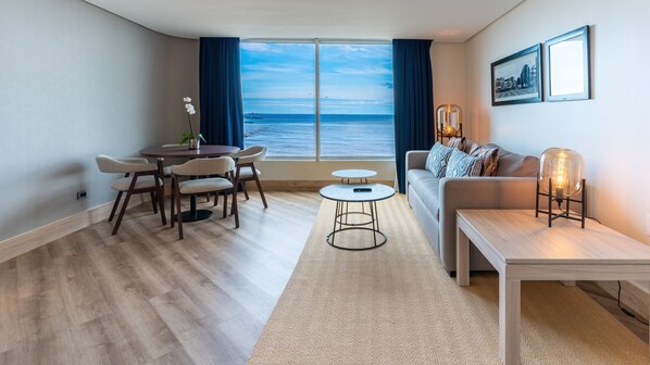 A modern living room with a view of the sea, a round dining table, a sofa, and a small side table. - Crowne Plaza Santo Domingo by IHG (Santo Domingo)