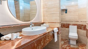 A bathroom with a white sink, a large mirror, a toilet, and a towel rack.