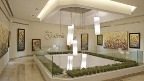An art gallery with a glass railing, artworks on the walls, and a central water feature. - Crowne Plaza Santo Domingo by IHG (Santo Domingo)