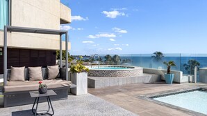 Eine Dachterrasse mit Pool, einer Sitzecke und Blick auf den Ozean.