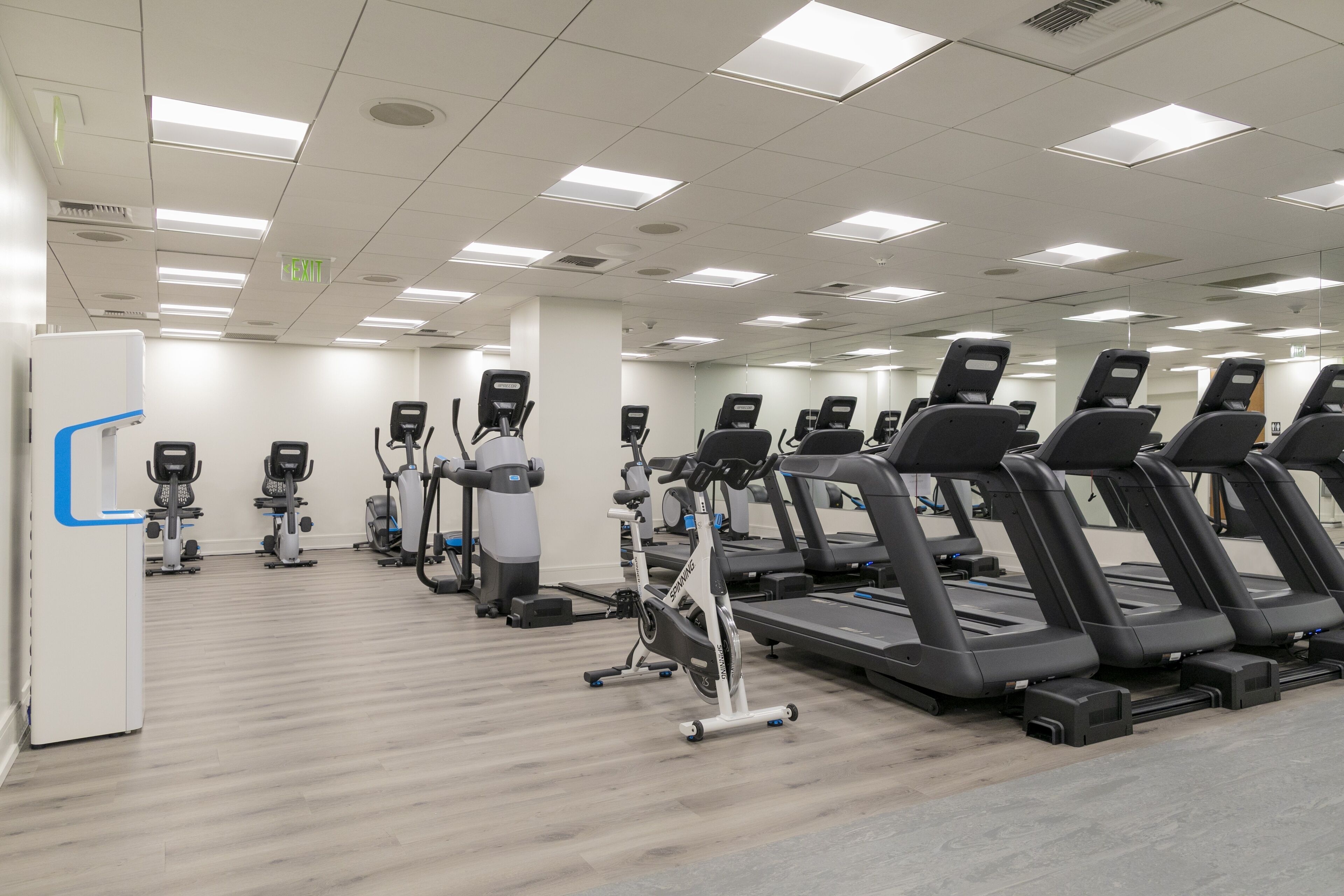 A gym with multiple treadmills, stationary bikes, and elliptical machines.