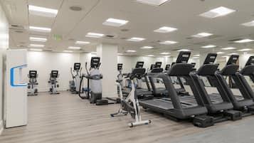 A gym with multiple treadmills, stationary bikes, and elliptical machines.