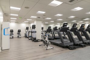 Un gimnasio con cintas de correr, bicicletas estáticas y máquinas elípticas.