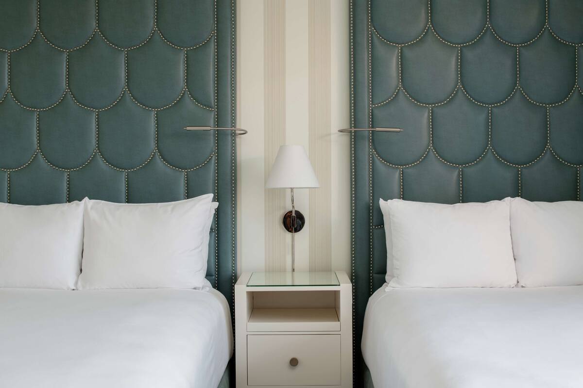 Une chambre d’hôtel avec deux lits, une table de chevet avec une lampe et un mur à rayures.