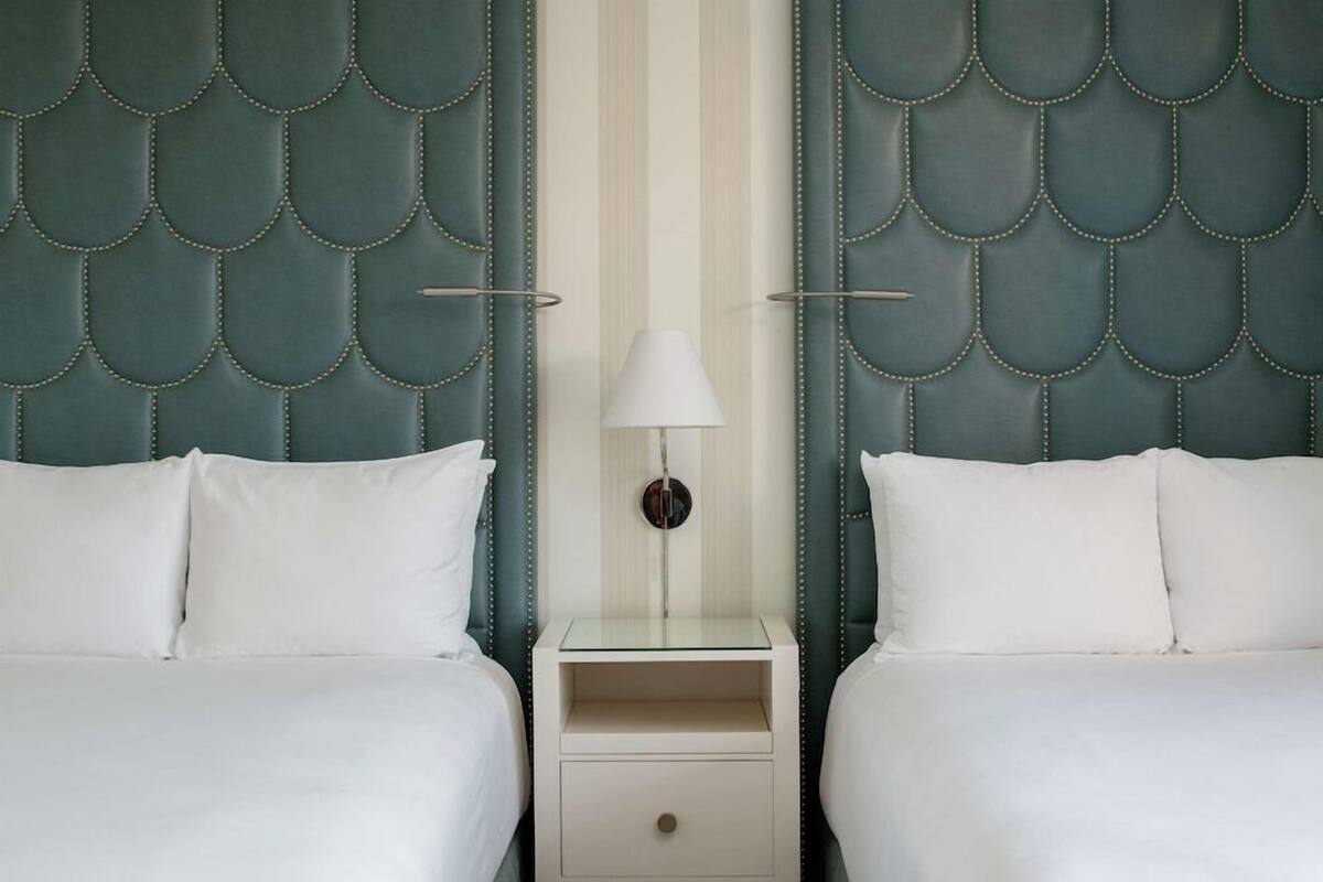 Une chambre d’hôtel avec deux lits, une table de chevet avec une lampe et un mur à rayures.