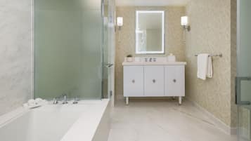 A modern bathroom with a glass-enclosed shower, a large white bathtub, a vanity with a mirror, and a towel rack.