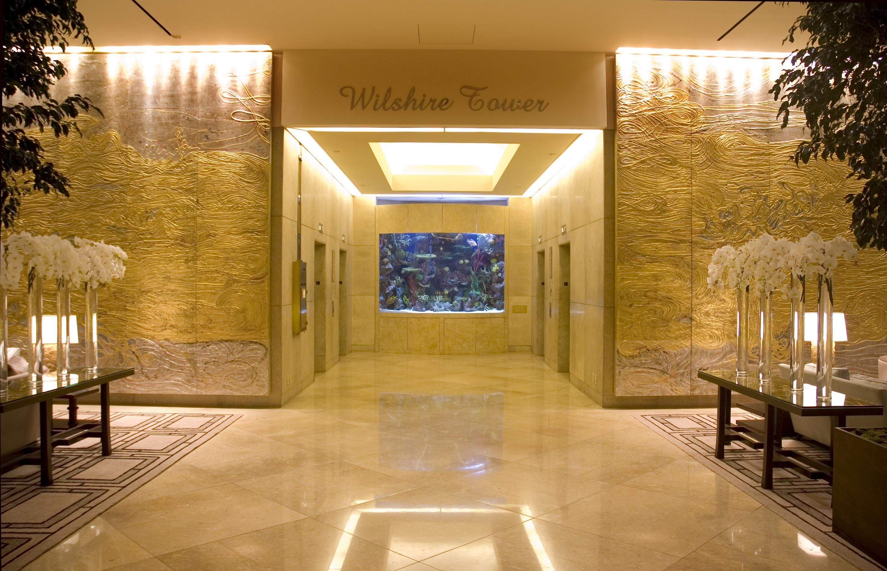 En hotellobby med ett stort akvarium i mitten, en receptionsdisk och en skylt med texten ”Wilshire Tower”.