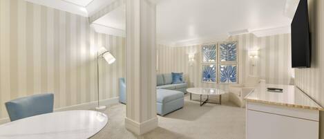 A hotel room with a dining table, a sofa, a TV, and a patterned carpet.