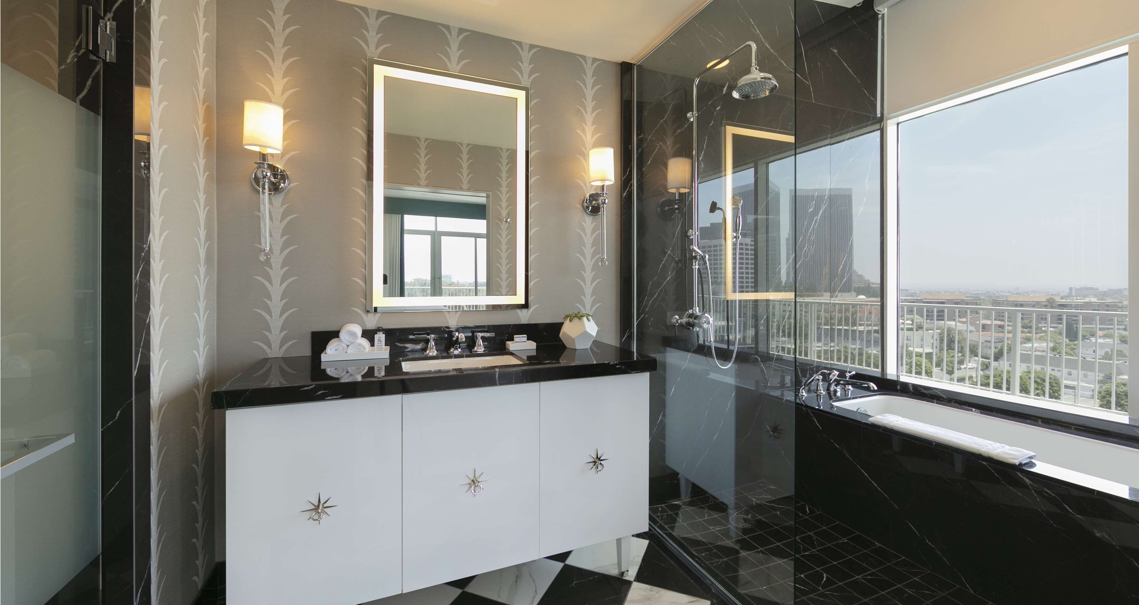 A modern bathroom with a black and white marble vanity, a large mirror, and a glass-enclosed shower.