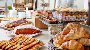 A buffet with various baked goods including pastries, bread, and rolls. - The Beverly Hilton (Beverly Hills)