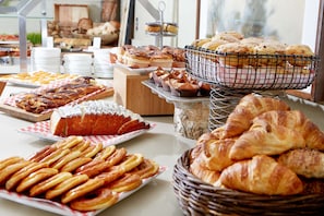 Un bufé con diversas opciones de panadería, incluyendo pasteles, pan y bollos.