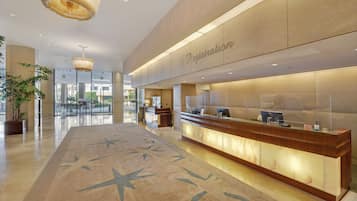 A hotel reception area with a registration desk, a large star-patterned carpet, and a modern chandelier.