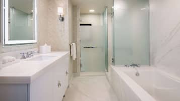 Un baño moderno con dos lavamanos, una bañera amplia y una ducha con cerramiento de vidrio.