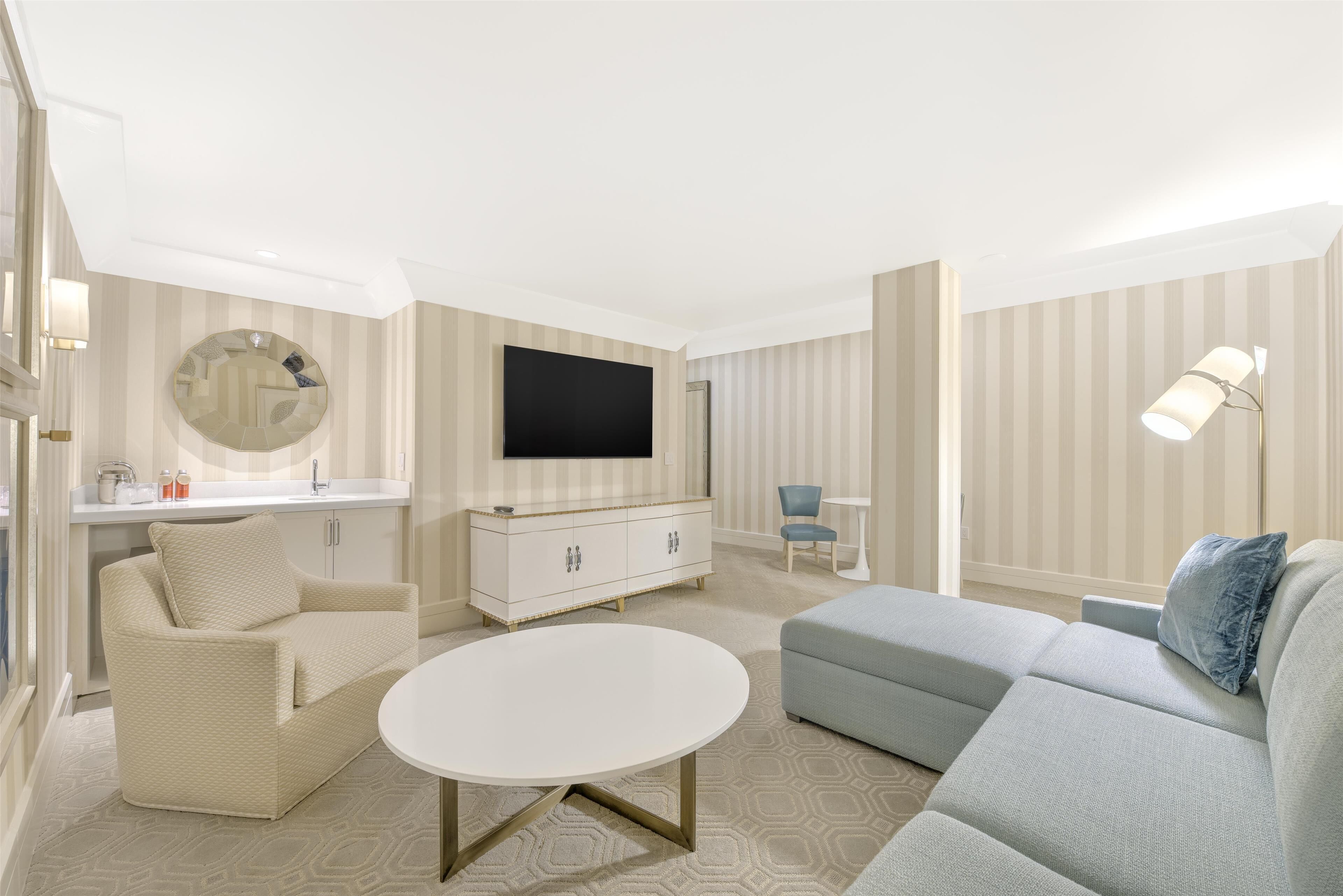 A modern living room with a sofa, a coffee table, a TV, and a lamp.