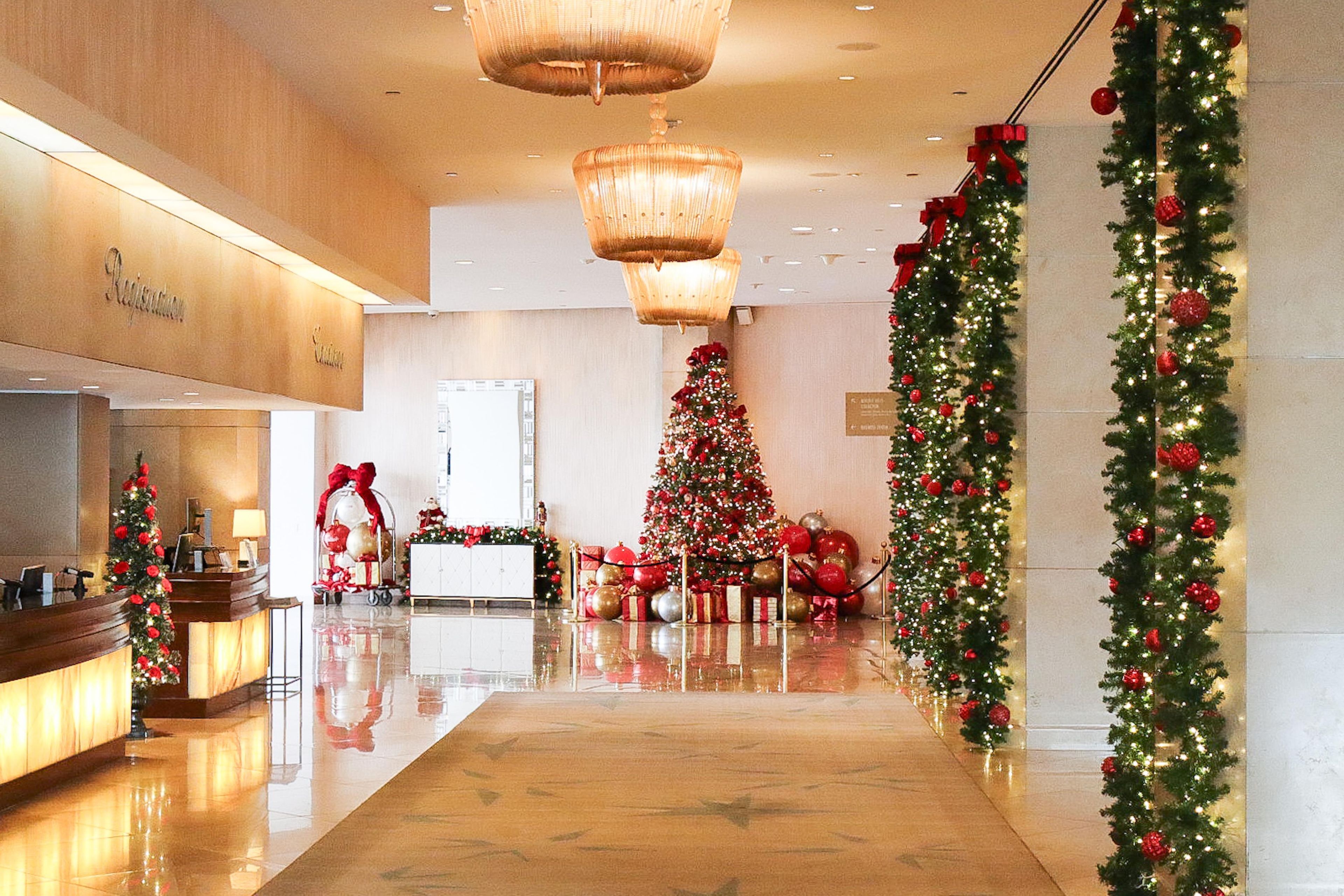 Un hall de hotel con un árbol de Navidad, una recepción y una pared adornada con guirnaldas.
