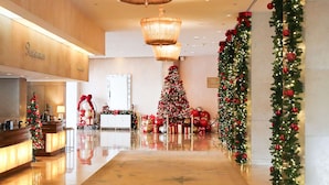 A spacious lobby with a reception desk, a Christmas tree, and festive decorations. - The Beverly Hilton (Beverly Hills)