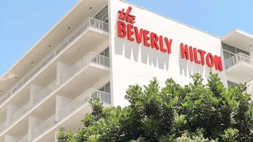 The exterior of the Beverly Hilton hotel with a white facade and red lettering.
