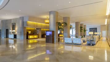 A spacious lobby with a reception desk, seating area, and a large plant.
