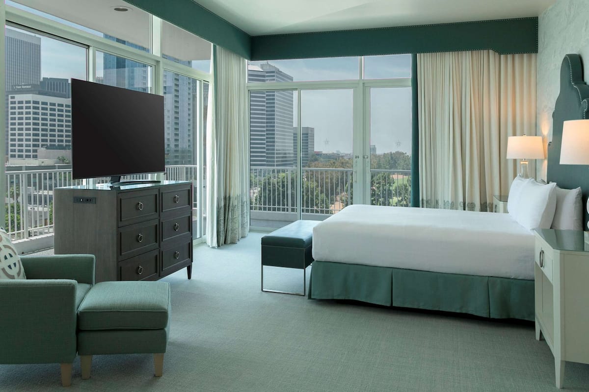 Une chambre d’hôtel moderne équipée d’un grand lit, d’une télévision, d’une commode et d’une chaise.