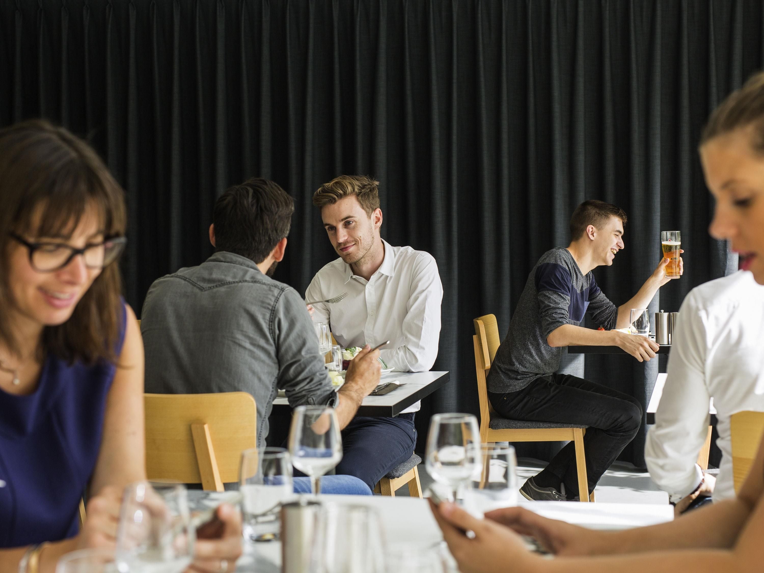 A group of people dining at a restaurant with a black curtain backdrop.