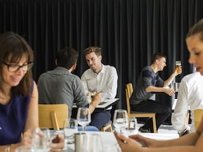A group of people dining at a restaurant with a black curtain backdrop. - Mercure Nancy Centre Gare (Nancy)
