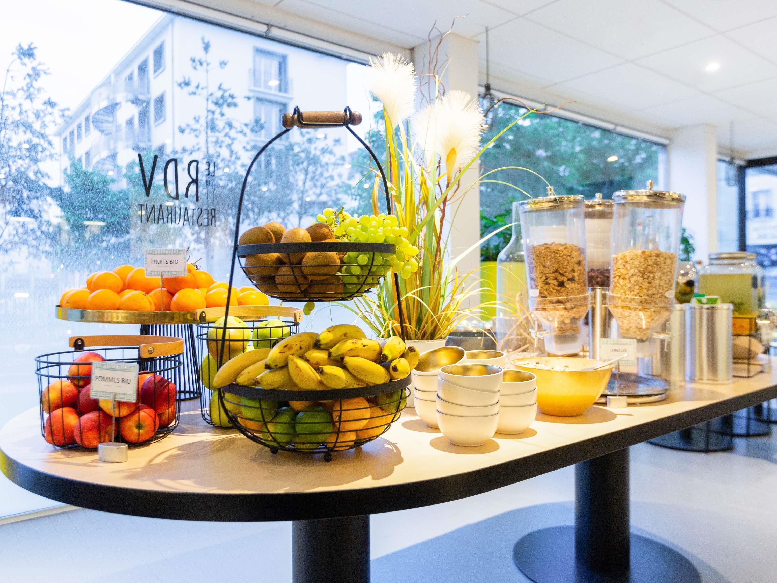 A breakfast buffet with fruits, bananas, apples, and grains.