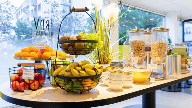 Um buffet de café da manhã com frutas, bananas, maçãs e cereais.