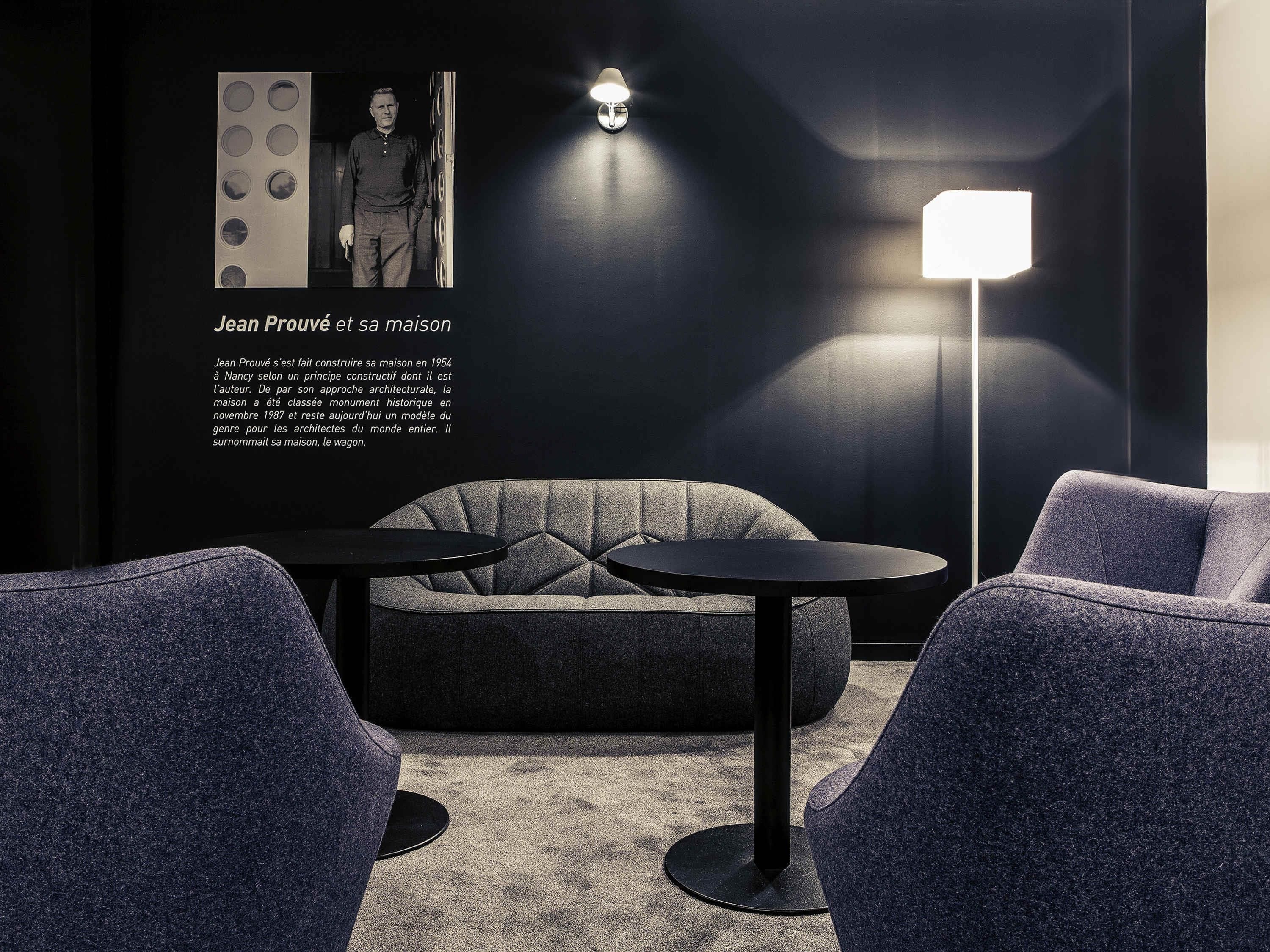 A modern interior with a sofa, two round tables, and a floor lamp.