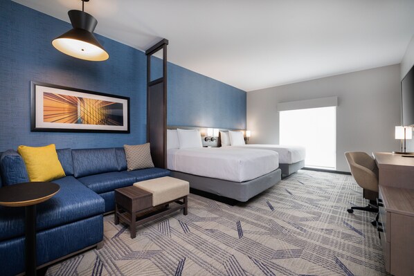 A hotel room with a blue wall, a large bed, a sofa, a desk, and a chair. - Hyatt Place San Carlos (San Carlos)