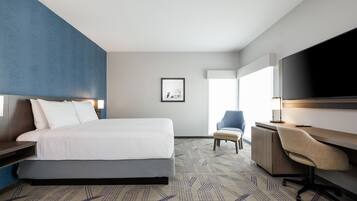 Hotelkamer met een bed, een bureau, een stoel, een televisie en een ingelijst schilderij aan de muur.