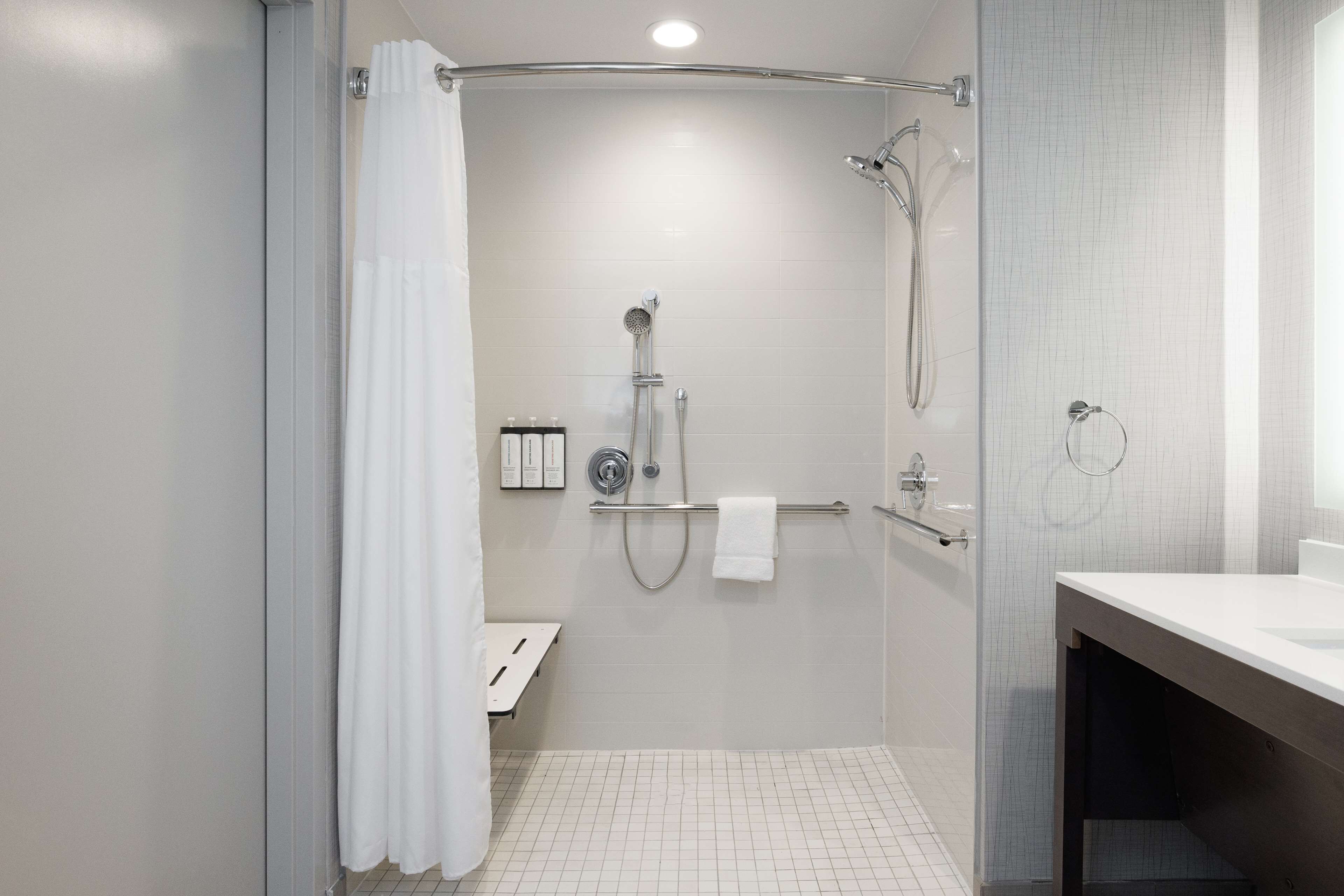 Une salle de bain moderne avec une douche à parois de verre, un lavabo blanc et un porte-serviettes.