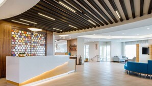 A modern reception area with a white reception desk, wooden paneling, and a colorful hexagonal wall design.