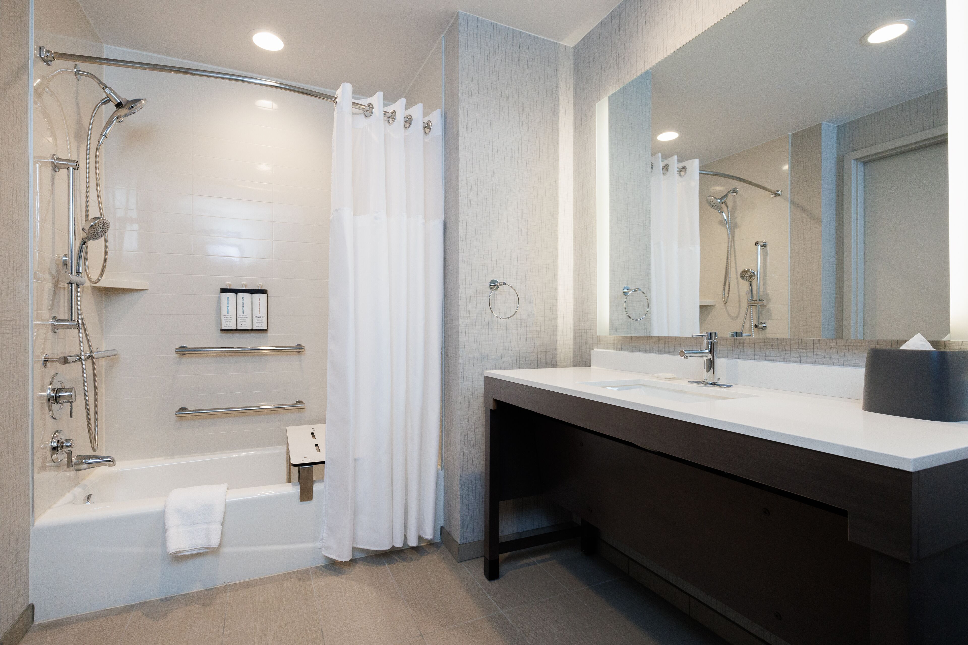 A modern bathroom with a bathtub, shower, and vanity with a mirror.