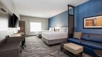 A hotel room with a bed, a sofa, a desk, and a TV.