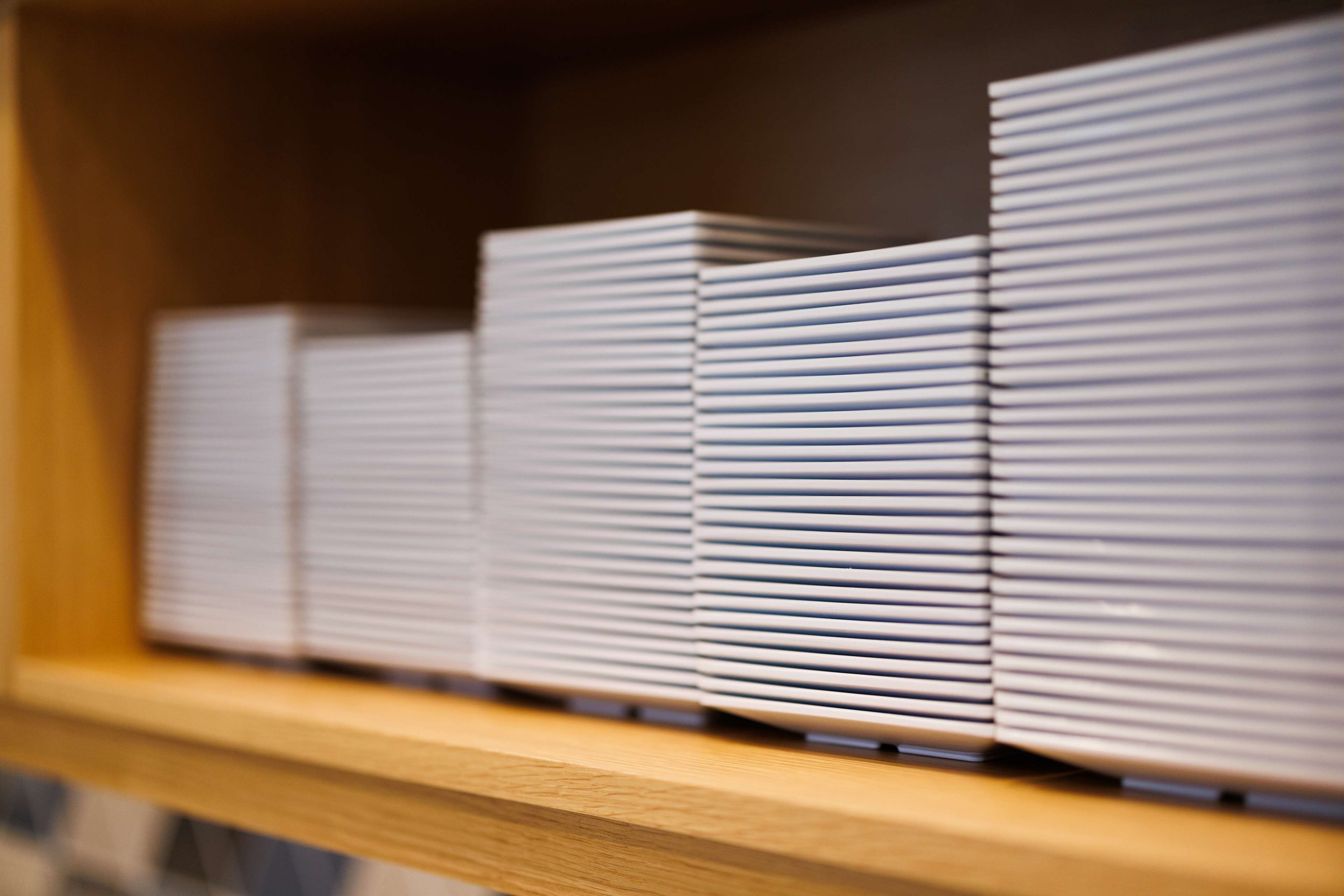 Una estantería de madera con objetos blancos ordenados, posiblemente libros o carpetas.