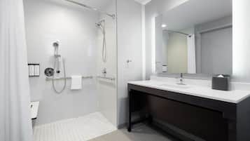 A modern bathroom with a glass-enclosed shower, a dark vanity with a white sink, and a large mirror.