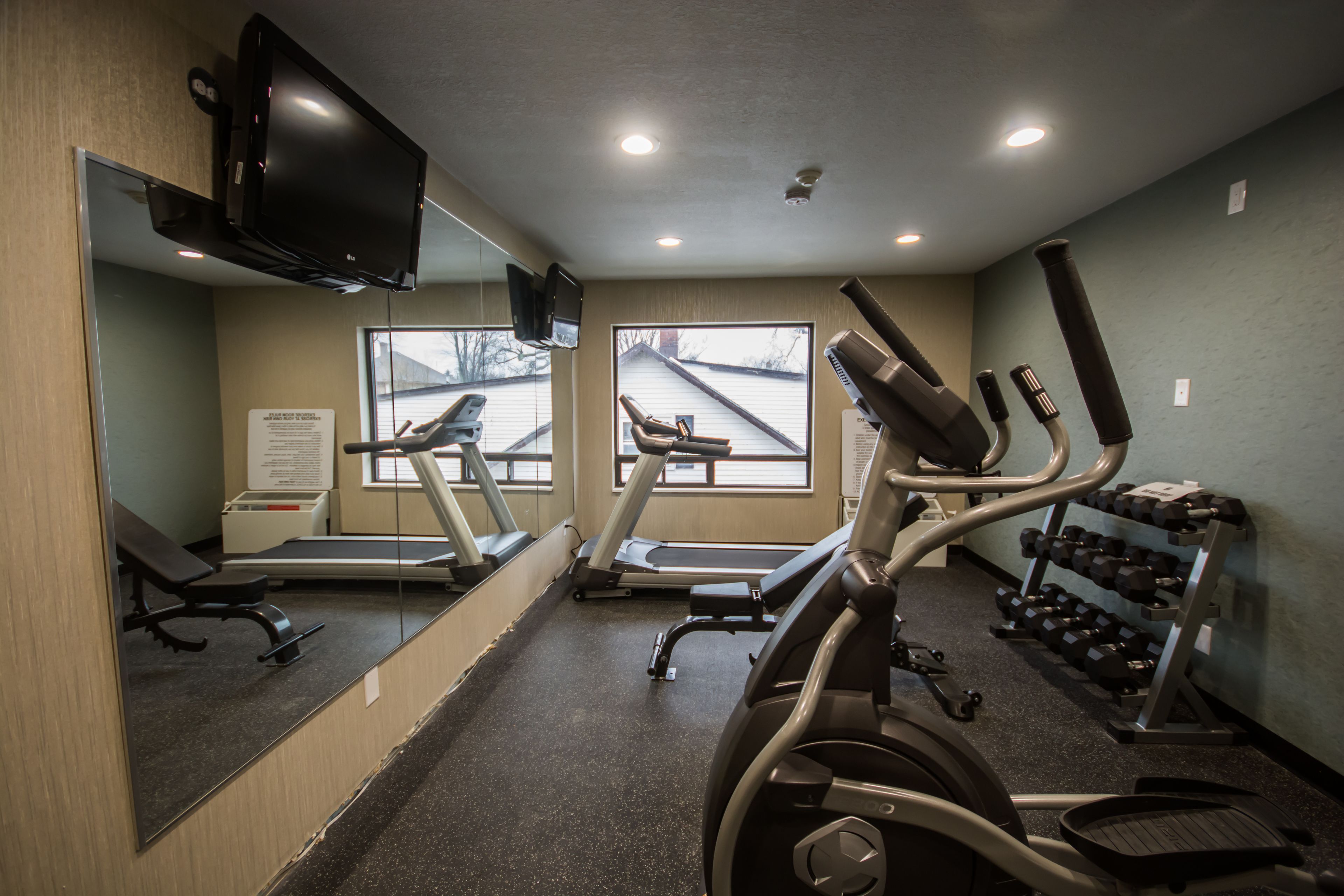 Une salle de sport équipée de matériel d’exercice, d’un tapis de course et d’un miroir.