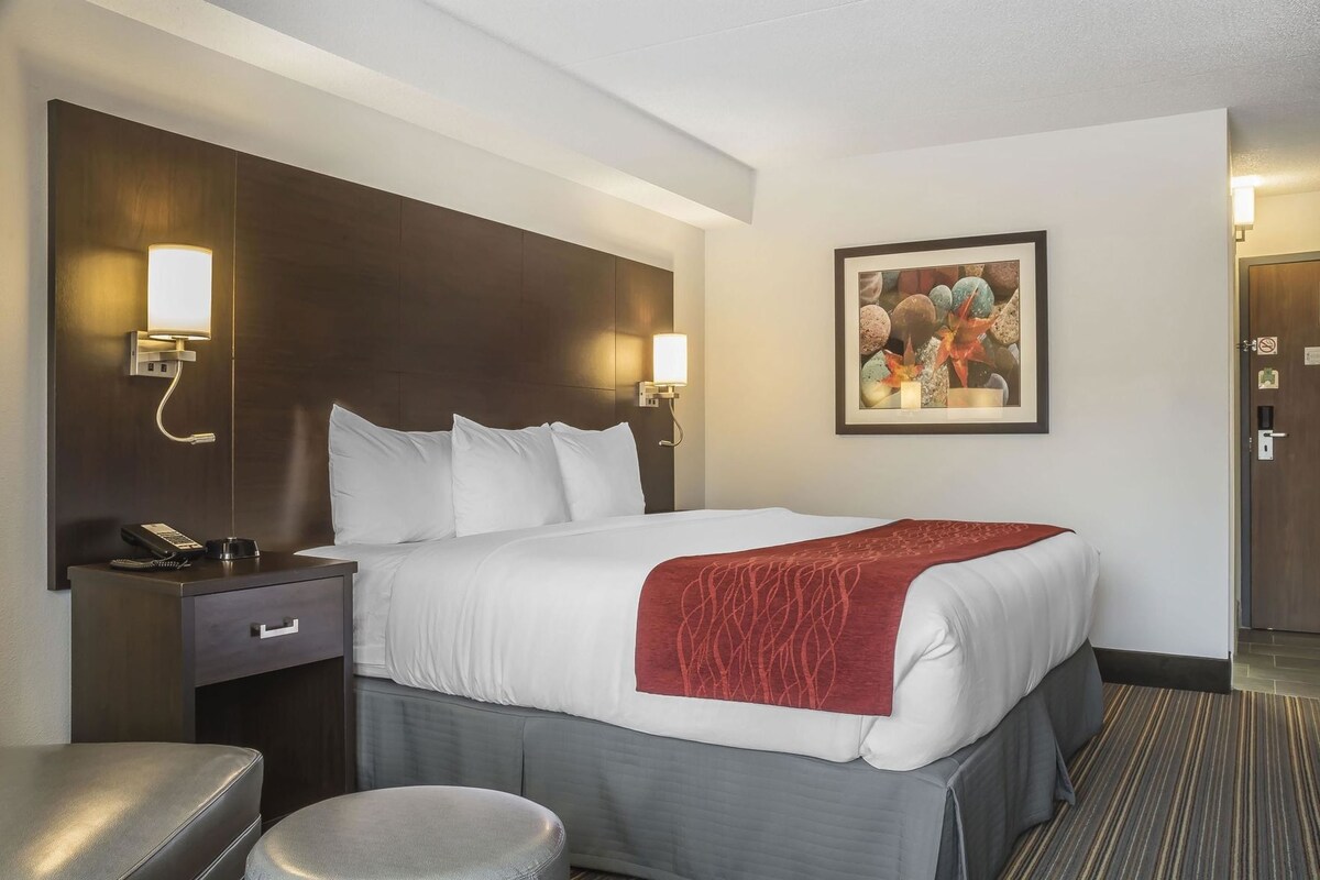 A hotel room with a large bed, bedside tables, a desk, and a chair.