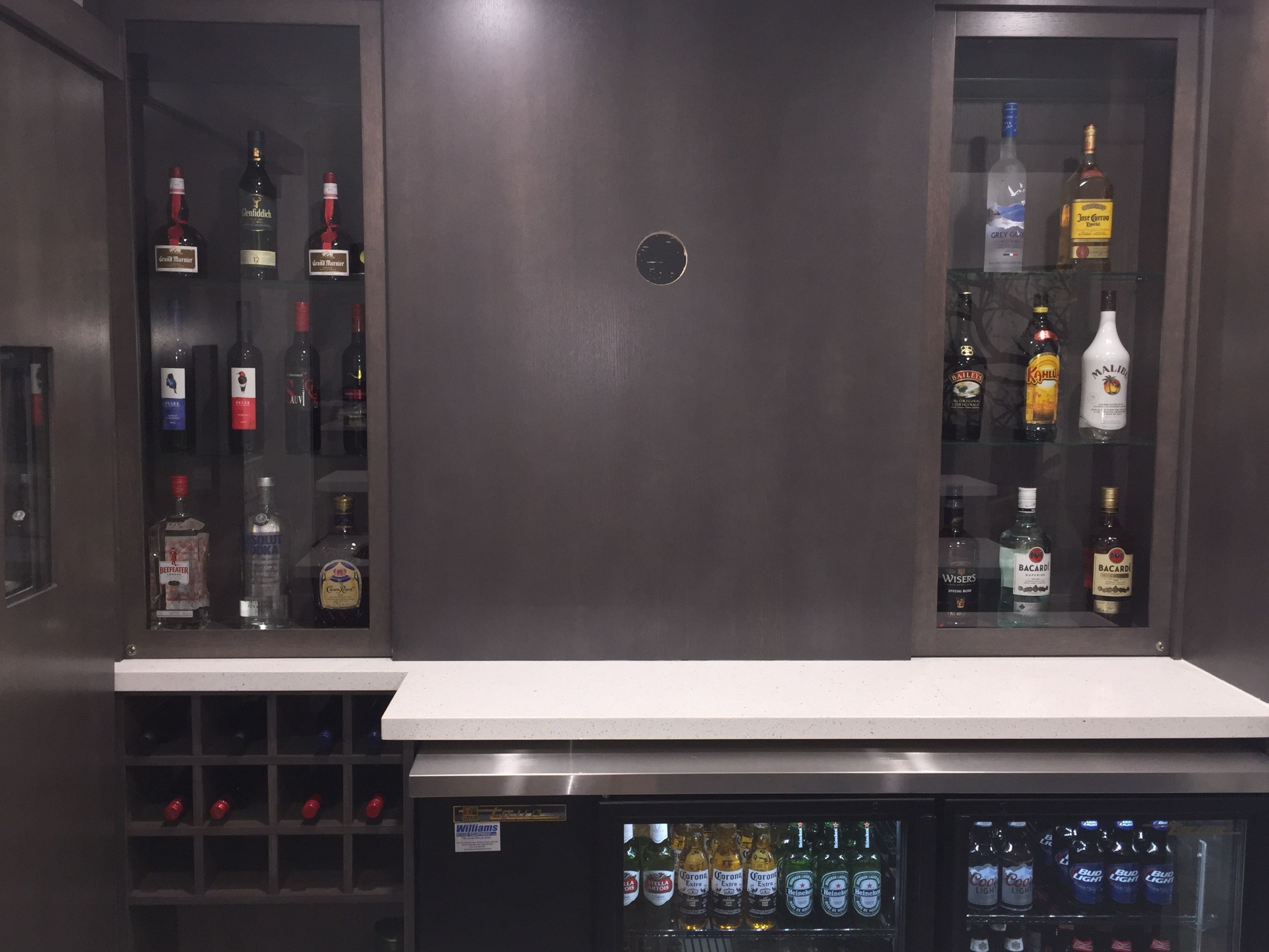 A bar area with shelves of liquor bottles and a refrigerated display of beer.