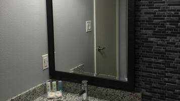 A bathroom with a granite countertop, a sink, a mirror, and a door.
