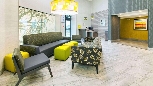 A lobby with a sofa, chairs, and ottomans in a modern design.