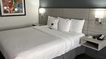 A modern hotel room with a large bed, a nightstand with a phone, and a wall-mounted light fixture.