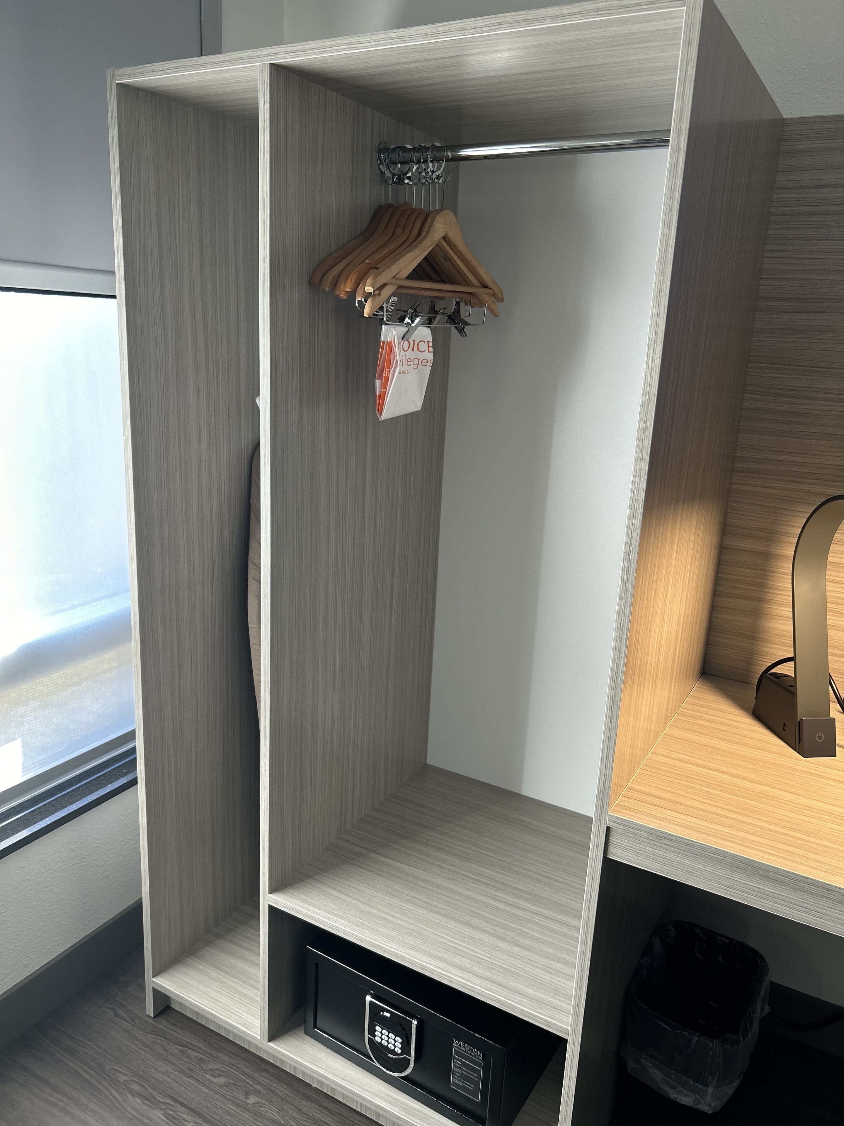 Ein moderner Kleiderschrank mit Kleiderstange, integriertem Schuhfach und einem kleinen Mülleimer.