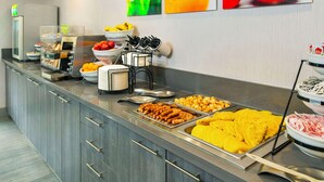 A buffet counter with various food items, including fruits, vegetables, and prepared dishes.